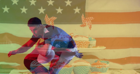 Crouching men posing on white studio floor, with US flag, red white blue cupcakes, star pinwheels. Patriotism, celebration, camaraderie, vibrant, energetic, festive, traditionの写真素材