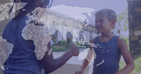 Exchanging kids wearing gray tank tops fist-bumping in suburban courtyard, with world map overlay. Friendship, collaboration, unity, diversity, community, outdoor, youthfulの写真素材