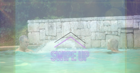 Two friends in swim trunks playfully splashing each other in outdoor private pool, with water jet....
