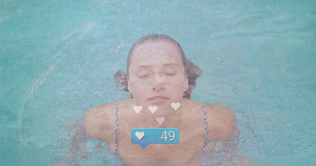 Floating woman wearing swimsuit on turquoise pool surface, with heart icons and 49-count badge. Relaxation, serenity, aquatic, leisure, calm, refreshment, wellnessの写真素材