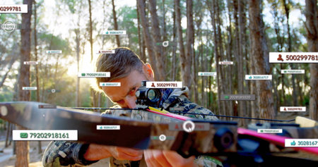 Aiming mature male wearing camo holding crossbow with scope in pine forest, with digital overlays. Hunter, tactical, precision, outdoor, stealth, technology, wildernessの写真素材