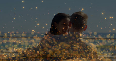 Smiling woman hugging man on waterfront deck, with metal railing and golden bokeh lights. Romantic, affection, serenity, outdoor, twilight, dreamy, happinessの写真素材