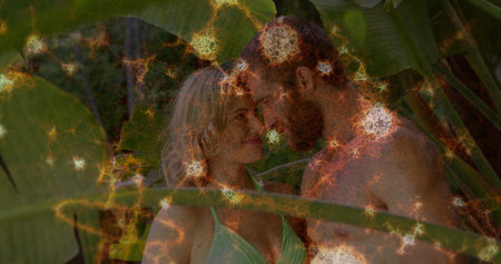 Standing couple in swimwear touching foreheads on deck under tropical leaves, with glowing orbs. Romance, outdoor, lush, serenity, intimacy, vacation, natureの写真素材