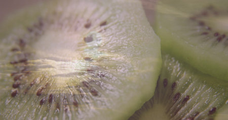 Displaying three green kiwi fruit slices on brown cutting board, highlighting radial seed pattern. Fresh produce, healthy lifestyle, vibrant colors, organic, natural, food presentation, culinaryの写真素材