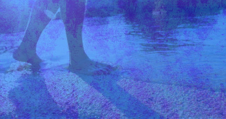 Wading adult male stepping in shallow shoreline water, with rolled pant cuffs, pebbles and ripples. Seashore, tranquility, reflection, outdoors, leisure, minimalism, serenityの写真素材