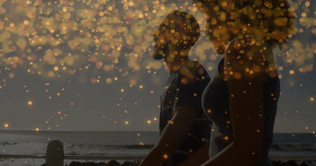 Standing fit couple gazing at ocean horizon on seaside walkway, wooden railing, golden bokeh lights. Seascape, wellness, relaxation, outdoor, lifestyle, tranquility, warmの写真素材