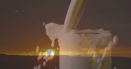 Pouring milk stream into clear glass, frothing overflow on rural horizon at sunset with tree line. Fluid dynamics, serenity, pastoral, craftsmanship, minimalism, nature, organicの写真素材