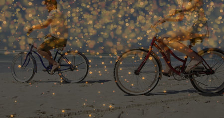 Riding couple pedaling red and blue cruiser bicycles on sandy shoreline, with golden light overlay. Leisure, adventure, companionship, serenity, landscape, outdoor, recreationalの写真素材