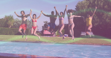 Holding hands, six friends in swimsuits leaping into backyard pool with checkered picnic blanket. Vacation, leisure, wellness, outdoor, tropical, summertime, lifestyleの写真素材