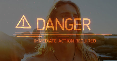 Standing shirtless man on rocky coast at sunset, showing overlay DANGER IMMEDIATE ACTION REQUIRED. Male, sunset, coastal, warning, alert, digital, natureの写真素材