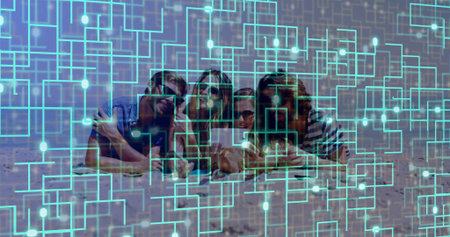 Lying friends wearing sunglasses in summerwear scrolling on tablet on sandy beach, circuit overlay. Casual, leisure, lifestyle, modern, technology, relaxation, outdoorの写真素材