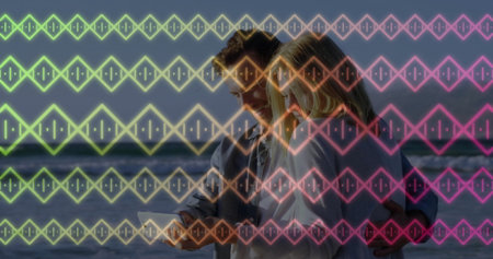 Holding tablet, blouse-clad woman and denim-shirt man embracing at ocean shore with diamond pattern. Romantic, technology, aquatic, abstract, serene, connection, contemporaryの写真素材