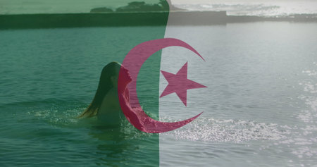 Emerging woman wearing swimsuit from bay near breakwater with Algerian flag overlay, copy space. Seascape, tranquility, serenity, leisure, outdoor, minimalist, reflectionの写真素材