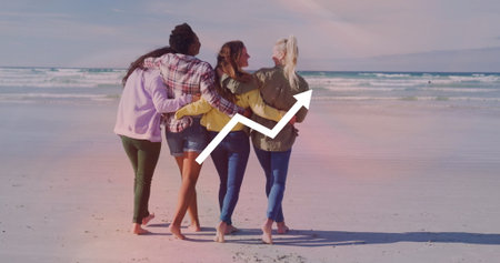 Walking women wearing jackets linking arms on beach, barefoot feet, ocean waves and graph overlay. Friendship, leisure, coastal, tranquility, teamwork, harmony, lifestyleの写真素材