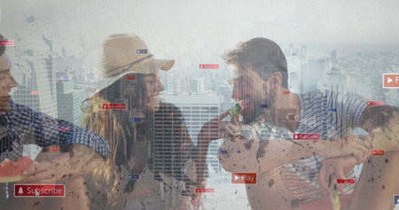 Laughing trio of friends sharing melon slices on rooftop balcony, with digital overlay icons. Socializing, outdoor, vibrant, leisure, urban, lifestyle, technologyの写真素材