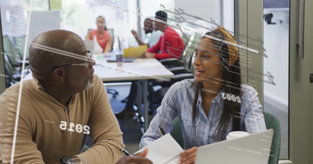 Sitting senior man in sweater and woman with headband discussing project at office, with laptop....