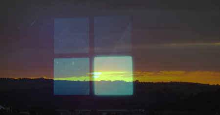 Reflecting four-pane digital grid through glass window over hills at sunset, with hill silhouettes....