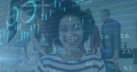 Smiling curly-haired woman in striped top using laptop in open-plan office, financial chart overlay. Collaboration, teamwork, office, data, finance, technology, professionalsの写真素材