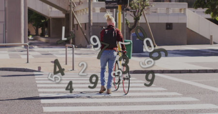 Man wearing red shirt pushing bicycle across zebra crosswalk at city intersection, with backpack....