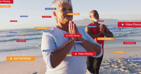 Yoga partners in athletic wear performing prayer-style pose on ocean edge, with social media alerts....