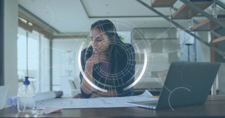 Reviewing female architect leaning over blueprints at modern home office, with sanitizer dispenser. Minimalist, professional, contemporary, creative, workspace, design, inspirationの写真素材