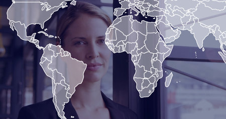 Standing businesswoman surveying skyline at corporate office window panels, with world map overlay. Professional, urban, contemporary, corporate, leadership, innovation, skylineの写真素材
