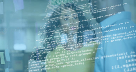 Reviewing team in green and blue shirts standing behind clear code screen at office, with monitors. Technology, collaboration, innovation, digital, workspace, programming, modernの写真素材