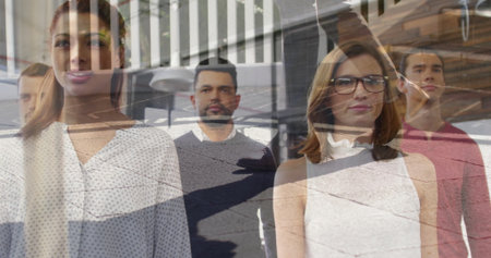 Posing office professionals behind glass partition in office, with pendant lights and desk lamp....
