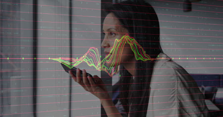 Issuing voice command woman holding smartphone by window at home office, with analytics overlay. Technology, communication, data, innovation, modern, workspace, professionalの写真素材