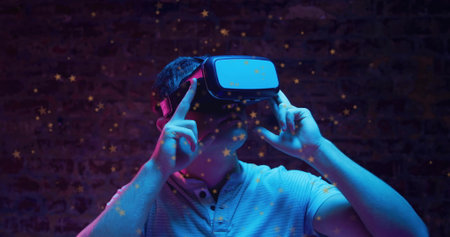 Man wearing light polo shirt adjusting virtual reality headset in studio, with star overlays....