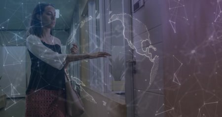 Touching glass panel businesswoman viewing globe nodes in office corridor with handbag, copy space. Futuristic, technology, networking, professional, modern, corporate, digitalの写真素材
