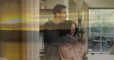 Embracing couple holding ceramic mug in living room with bookshelf, sliding doors, sunset overlay....