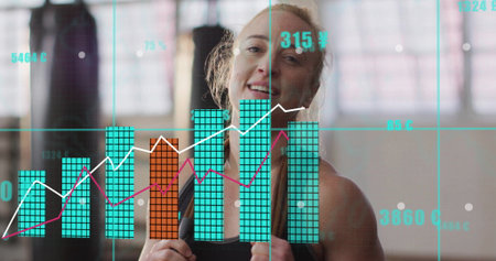 Smiling woman wearing black top and boxing gloves in gym, with punching bags, windows and overlay. Fitness, strength, empowerment, determination, wellness, training, modernの写真素材