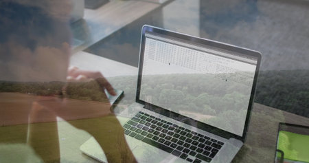 Woman coding on laptop and checking smartphone in home office with rural view, tablet, copy space....