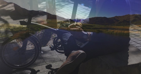 Seated man driving power wheelchair on tile plaza, with low stone bench and mountain lake backdrop. Accessibility, mobility, outdoor, modern, leisure, relaxation, scenicの写真素材