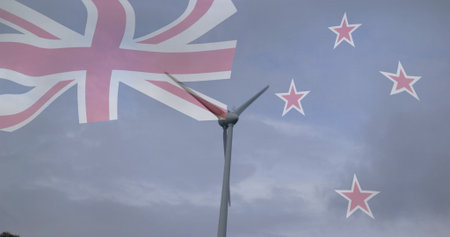 Standing tall wind turbine rotating slowly in rural landscape, with translucent New Zealand flag....