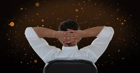 Male in white shirt clasping hands behind head in studio, with black office chair, glowing sparks. Professional, contemplative, modern, dynamic, abstract, motivational, figureの写真素材