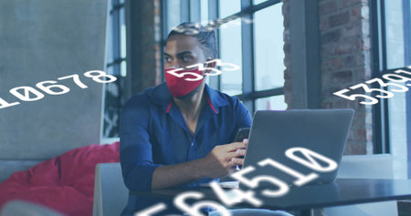 Analyzing man in red mask using laptop and smartphone in coworking lounge with numerical overlays. Technology, urban, contemporary, digital, workspace, innovation, productivityの写真素材