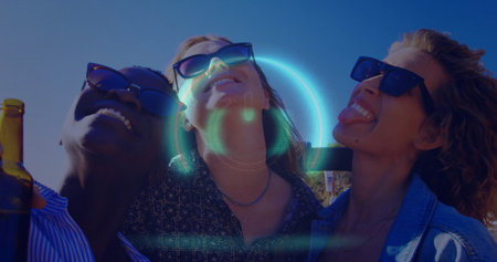 Smiling friends wearing sunglasses and necklaces leaning on rooftop terrace, holding beer bottle....