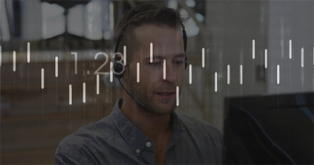 Monitoring agent wearing headset sitting at desk with screen in office, viewing overlay charts....