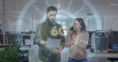 Colleagues discussing document while speaking into smartphone in office workspace, with 6G graphics....