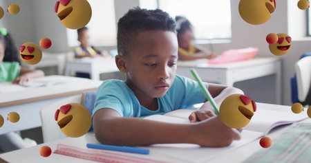 Writing boy wearing T-shirt using green pencil on open notebook at school desk, with ruler pen. Children, education, learning, classroom, focus, creativity, school suppliesの写真素材