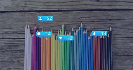 Showing colored pencils standing on worn wooden table with floating social media engagement icons....