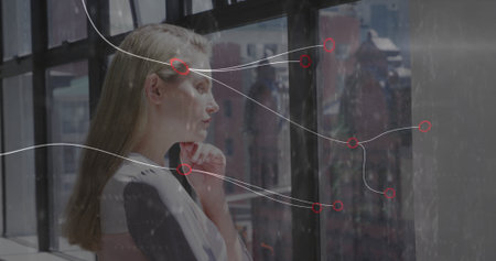 Standing adult woman resting chin on hand beside window in office, with data overlay, copy space....