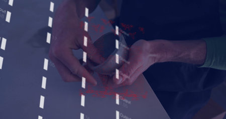 Holding smartphone in green-sleeved hands projecting coded text onto smooth tabletop at work desk....