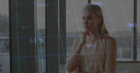 Standing blonde model gazing through office window at city view, with jewels, blue grid, copy space....