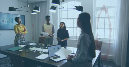 Collaborating business colleagues discussing reports around table in boardroom, with laptop charts....