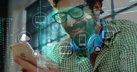 Smiling bearded man tapping smartphone screen in tech workspace, with holographic network icons....