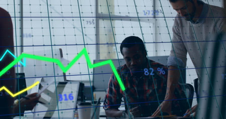 Collaborating analysts reviewing data on laptop at modern office, with overlaid digital charts....