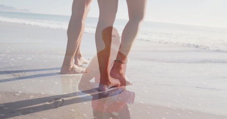 Walking two pairs of bare legs, silhouette standing on wet sand shoreline with footprints and waves. Seaside, nostalgia, tranquility, reflection, leisure, nature, harmonyの写真素材